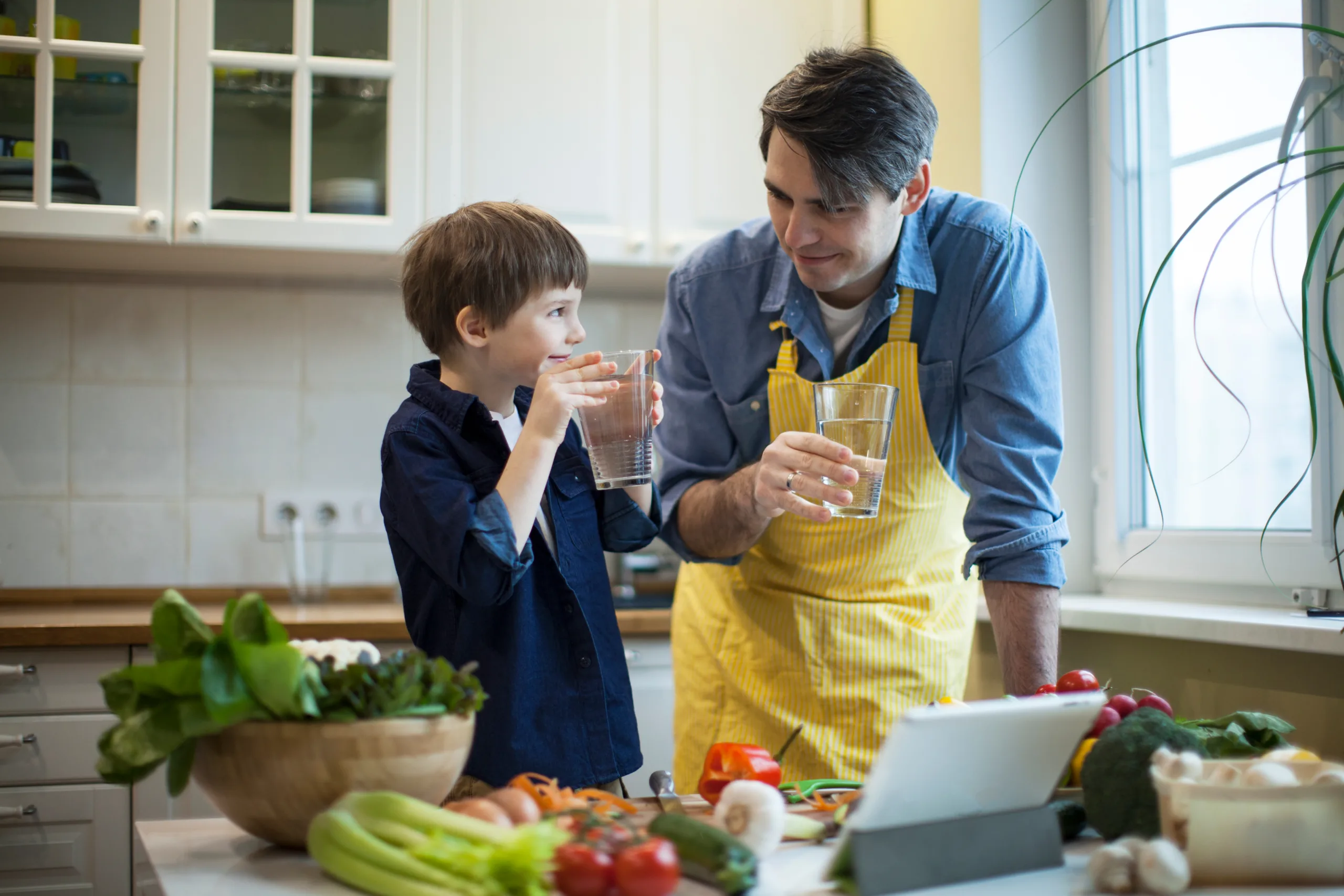 Pai e filho cozinhando e tomando água